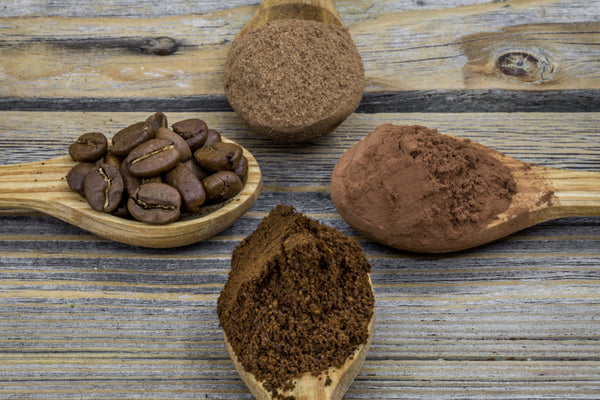 Bulk cacao powder and roasted cacao beans on wooden spoons representing manufacturing-grade cacao sourcing and ingredient performance testing