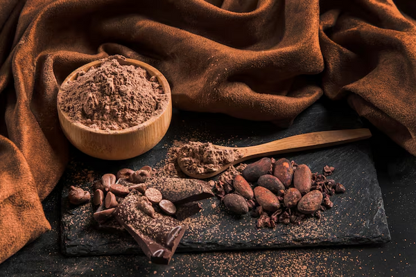 Cacao powder, cacao beans, and dark chocolate pieces displayed on a surface, representing premium cacao products and ingredients