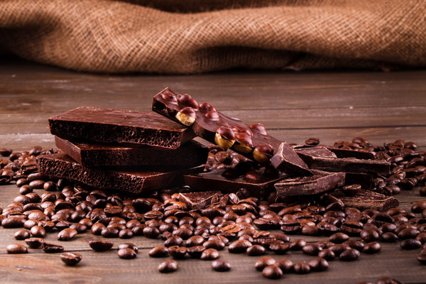 Dark chocolate bars and cacao beans displayed on a wooden surface, representing premium cacao processing, flavour development, and commercial chocolate production